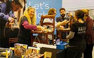 woman caning a chair at busy crafts fair